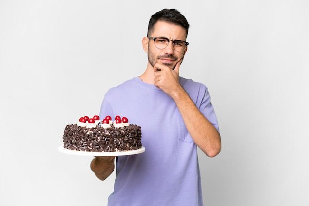 Jovem homem caucasiano segurando o bolo de aniversário isolado no pensamento de fundo branco