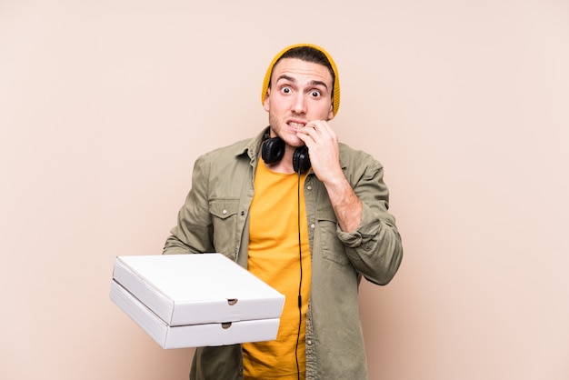 Jovem homem caucasiano segurando pizzas, roer unhas, nervosas e muito ansiosas.