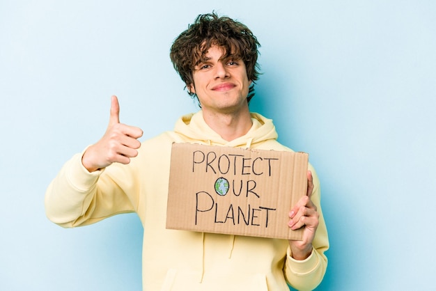 Jovem homem caucasiano segurando proteger nosso cartaz do planeta isolado em fundo azul