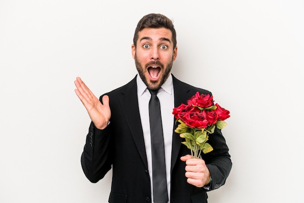 Jovem homem caucasiano segurando um buquê de flores isolado no fundo branco surpreso e chocado