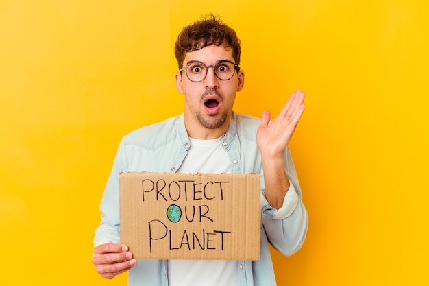 Jovem homem caucasiano segurando um cartaz de proteja nosso planeta