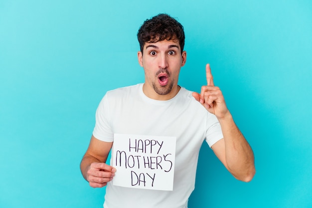 Jovem homem caucasiano segurando um cartaz do dia das mães feliz, isolado, tendo uma ideia