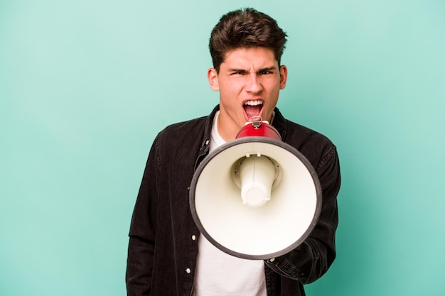 Jovem homem caucasiano segurando um megafone isolado no fundo branco gritando muito irritado e agressivo