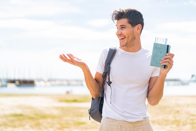 Jovem homem caucasiano segurando um passaporte ao ar livre com expressão facial de surpresa