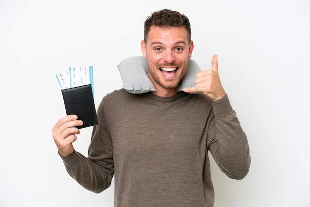 Jovem homem caucasiano segurando um passaporte isolado no fundo branco fazendo gesto de telefone Ligue-me de volta sinal