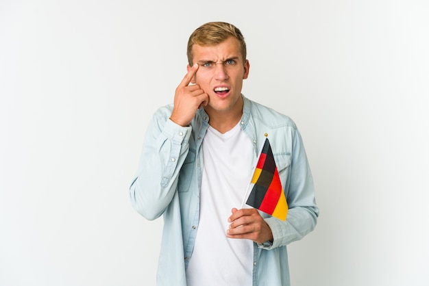 Jovem homem caucasiano segurando uma bandeira alemã isolada no espaço em branco sendo chocado, ela se lembrou de uma reunião importante.