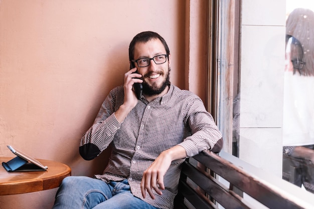 Jovem homem caucasiano sorrindo feliz falando no smartphone