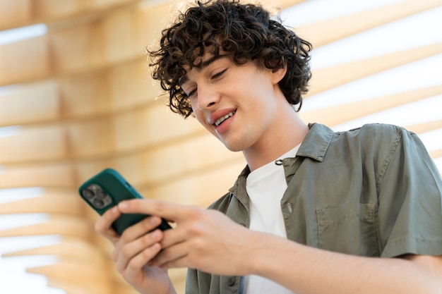 Jovem homem caucasiano sorrindo feliz usando smartphone na rua