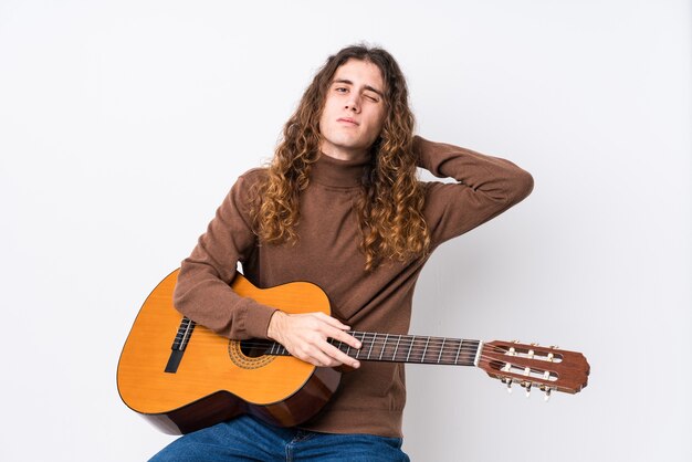 Jovem homem caucasiano tocando guitarra isolada tocando a parte de trás da cabeça, pensando e fazendo uma escolha.