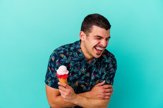 Jovem homem caucasiano tomando um sorvete na azul, rindo e se divertindo.