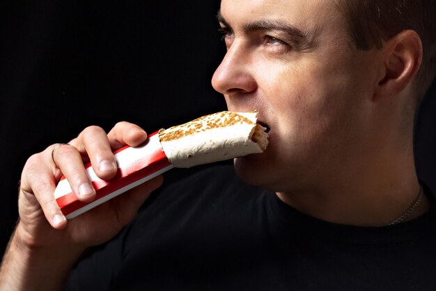 Foto jovem homem com fome comendo fast food conceito de dieta de comida não saudável