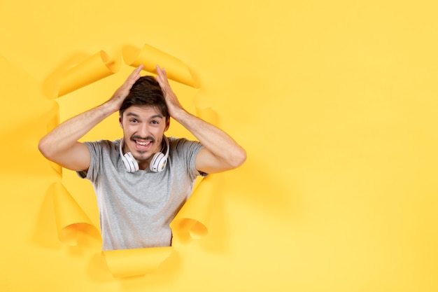 Jovem homem com fones de ouvido em papel amarelo fundo de música ultrassom áudio