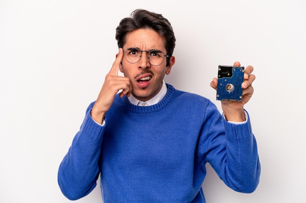 Jovem homem de informática caucasiano segurando um disco rígido isolado no fundo branco, mostrando um gesto de decepção com o dedo indicador