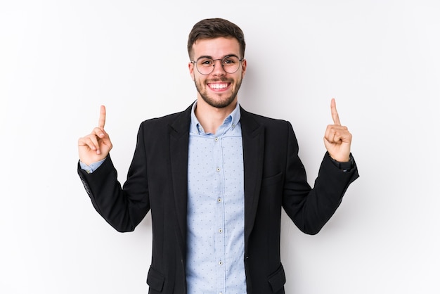 Jovem homem de negócios caucasiano posando em um fundo branco isolado Jovem homem de negócios caucasiano indica com os dois dedos anteriores mostrando um espaço em branco.