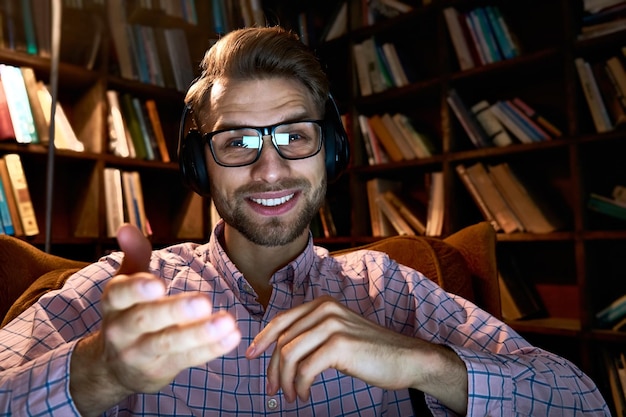 Foto jovem homem de negócios feliz estudante professor remoto tutor à distância usando fones de ouvido falando com câmera videoconferência chamadas de vídeo dando webinar aula on-line ensino ou streaming webcam visualização headshot