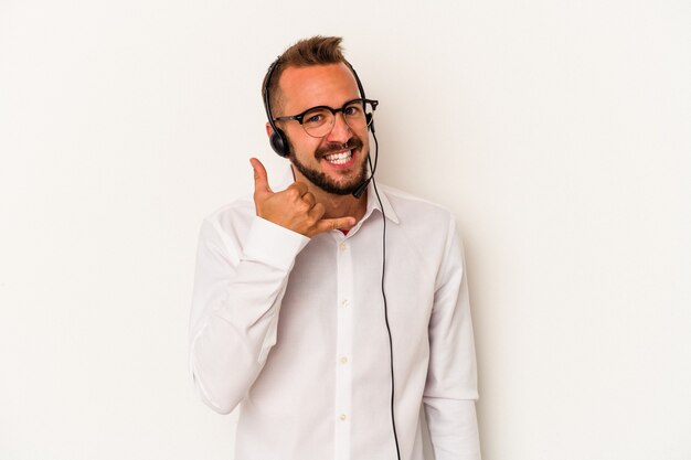 Jovem homem de telemarketing caucasiano com tatuagens isoladas no fundo branco, mostrando um gesto de chamada de telefone móvel com os dedos.