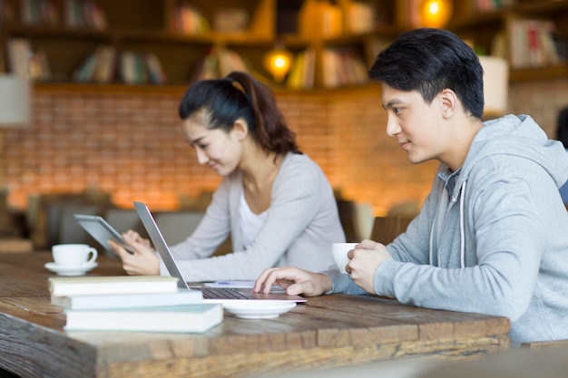 Jovem homem e mulher usando laptop e tablet digital em um café