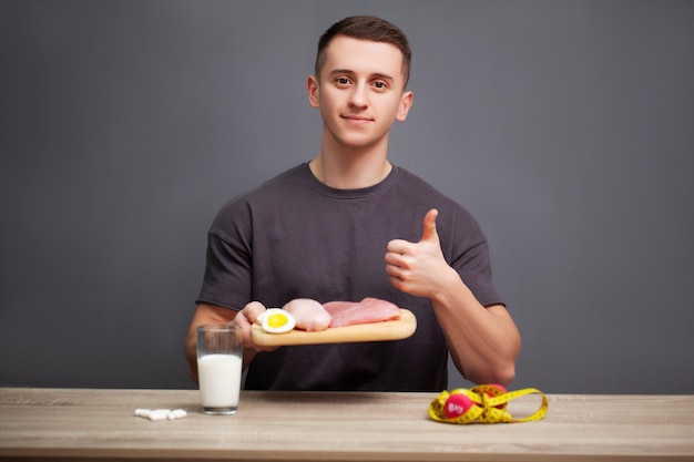 Jovem homem físico desportivo mantém uma refeição rica em proteínas para uma boa nutrição