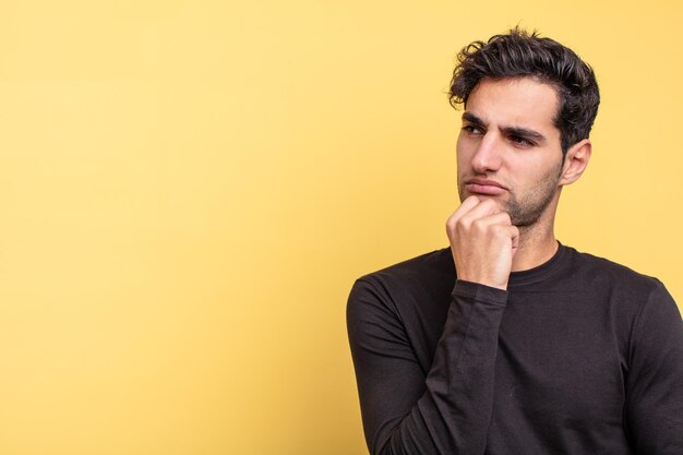 Jovem homem hispânico bonito com um espaço de cópia para o lado confuso conceito