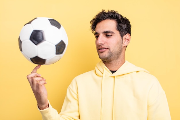 Jovem homem hispânico bonito com uma bola de futebol