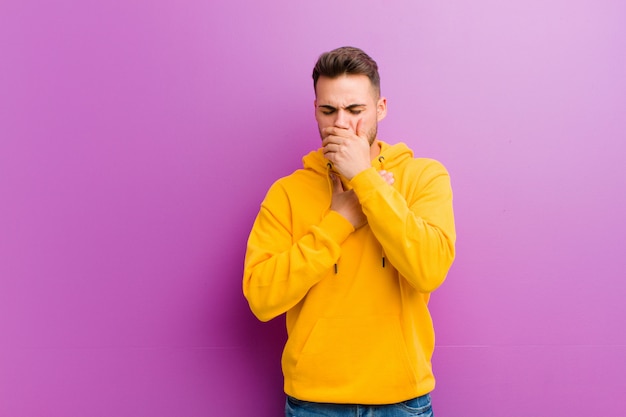 Jovem homem hispânico com olhar casual contra roxo