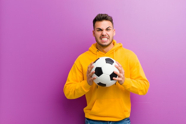 Jovem homem hispânico com uma bola de futebol