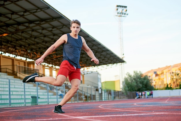 Jovem homem musculoso correndo na pista