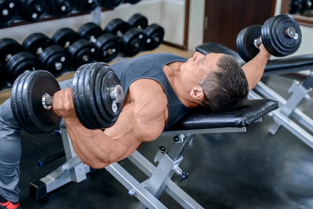 Jovem homem musculoso malhando na academia