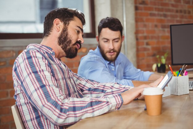 Jovem, homem negócios, olhar, tablete digital, enquanto, sentando, em, escritório