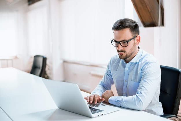 Jovem, homem negócios, trabalhando, com, laptop, em, escritório