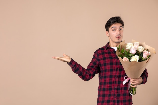 Foto jovem homem segurando flores bonitas na parede marrom