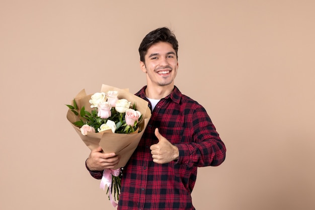 Jovem homem segurando flores bonitas na parede marrom