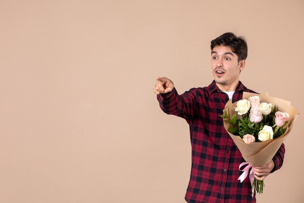 Jovem homem segurando flores bonitas na parede marrom