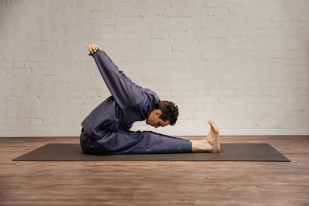 Jovem homem sem camisa forte pratica ioga no estúdio de yoga