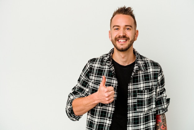 Foto jovem homem tatuado, caucasiano, isolado no fundo branco, sorrindo e levantando o polegar