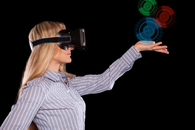 Jovem imersa em videogame interativo de realidade virtual fazendo gestos em fundo preto.