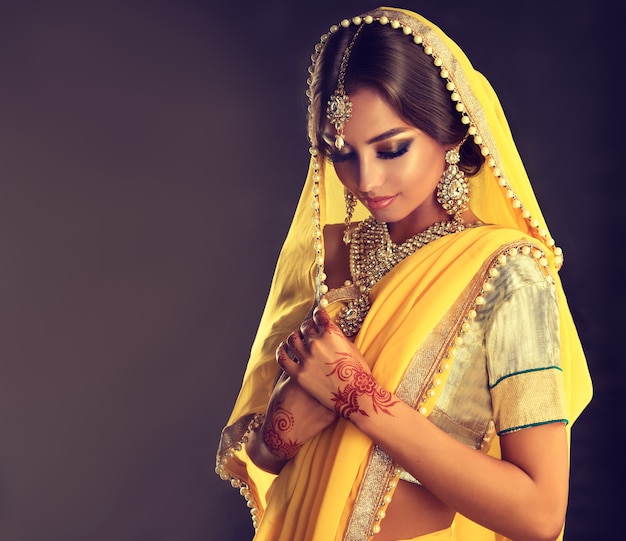 Jovem indiana de cabelos negros vestindo uma roupa chique lehenga choli Cabeça com véu, maquiagem esplêndida e conjunto de joias indianas chiques.