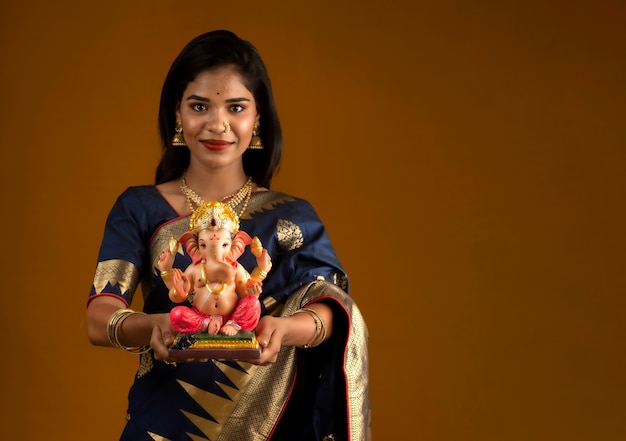 Foto jovem indiana feliz posando com a estátua de ganesha por ocasião do festival de ganesh