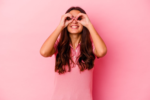 Jovem indiana isolada em rosa mostrando sinal de aprovação sobre os olhos