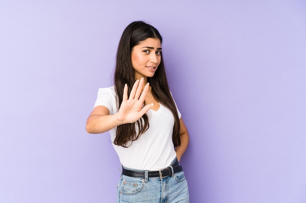 Jovem indiana isolada em um fundo roxo, rejeitando alguém com um gesto de nojo.