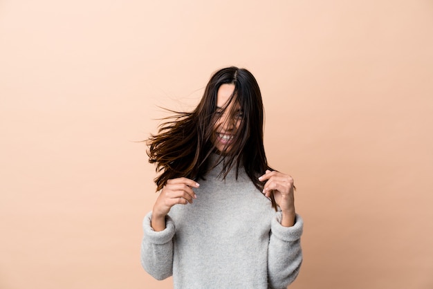 Foto jovem indiana mexendo no cabelo, isolado em um fundo bege.