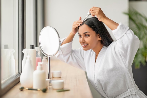Jovem indiana positiva usando óleo nutritivo para cabelo
