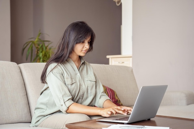 Jovem indiana usando laptop trabalhando em home office