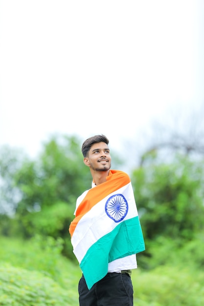 Jovem indiano agitando a bandeira nacional indiana sobre o fundo da natureza