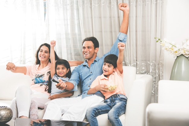 Jovem indiano asiático família assistindo tv juntos, enquanto está sentado no sofá, foco seletivo