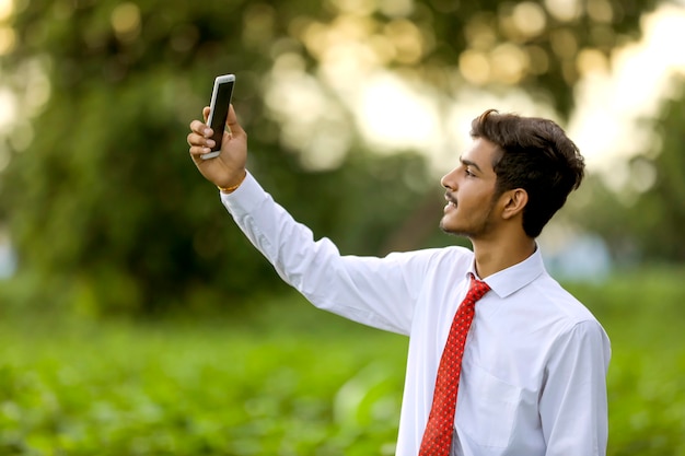 Jovem indiano clicando em selfie com celular