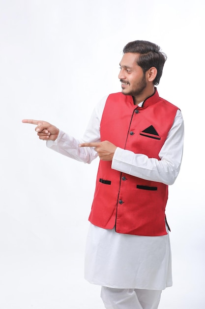 Jovem indiano com roupas tradicionais e mostrando a direção no fundo branco.