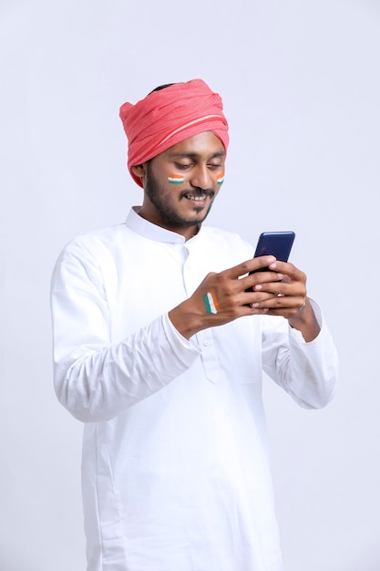 Jovem indiano comemorando o dia da independência ou dia da república e usando o smartphone.