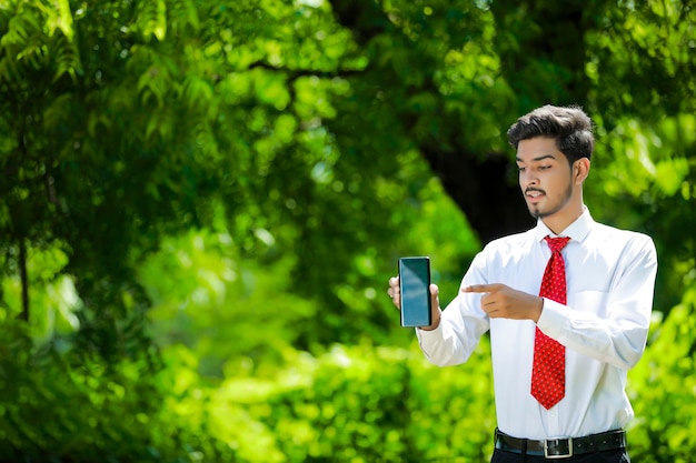 Jovem indiano confiante mostrando seu telefone inteligente