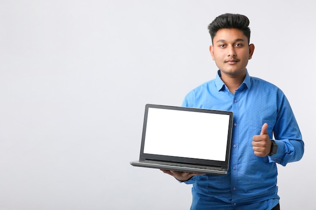 Jovem indiano mostrando a tela do laptop em fundo branco.